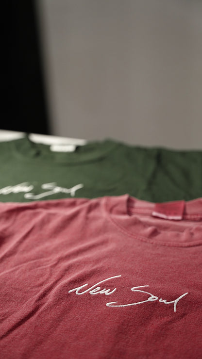 Two t-shirts, one green and one maroon, with 'New Soul' text on a blurred background.
